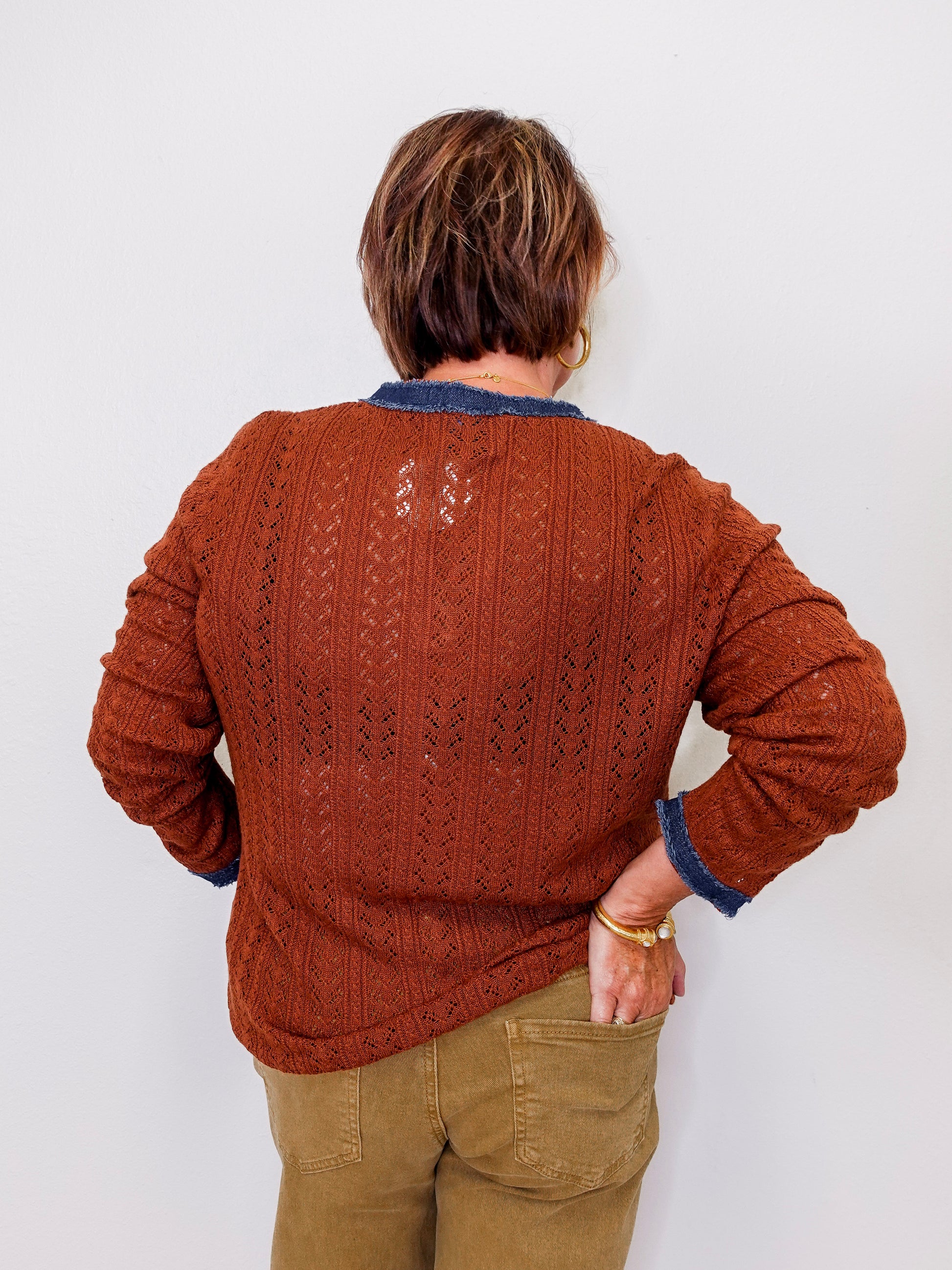 Person wearing a brown knitted sweater with a white background