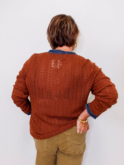 Person wearing a brown knitted sweater with a white background