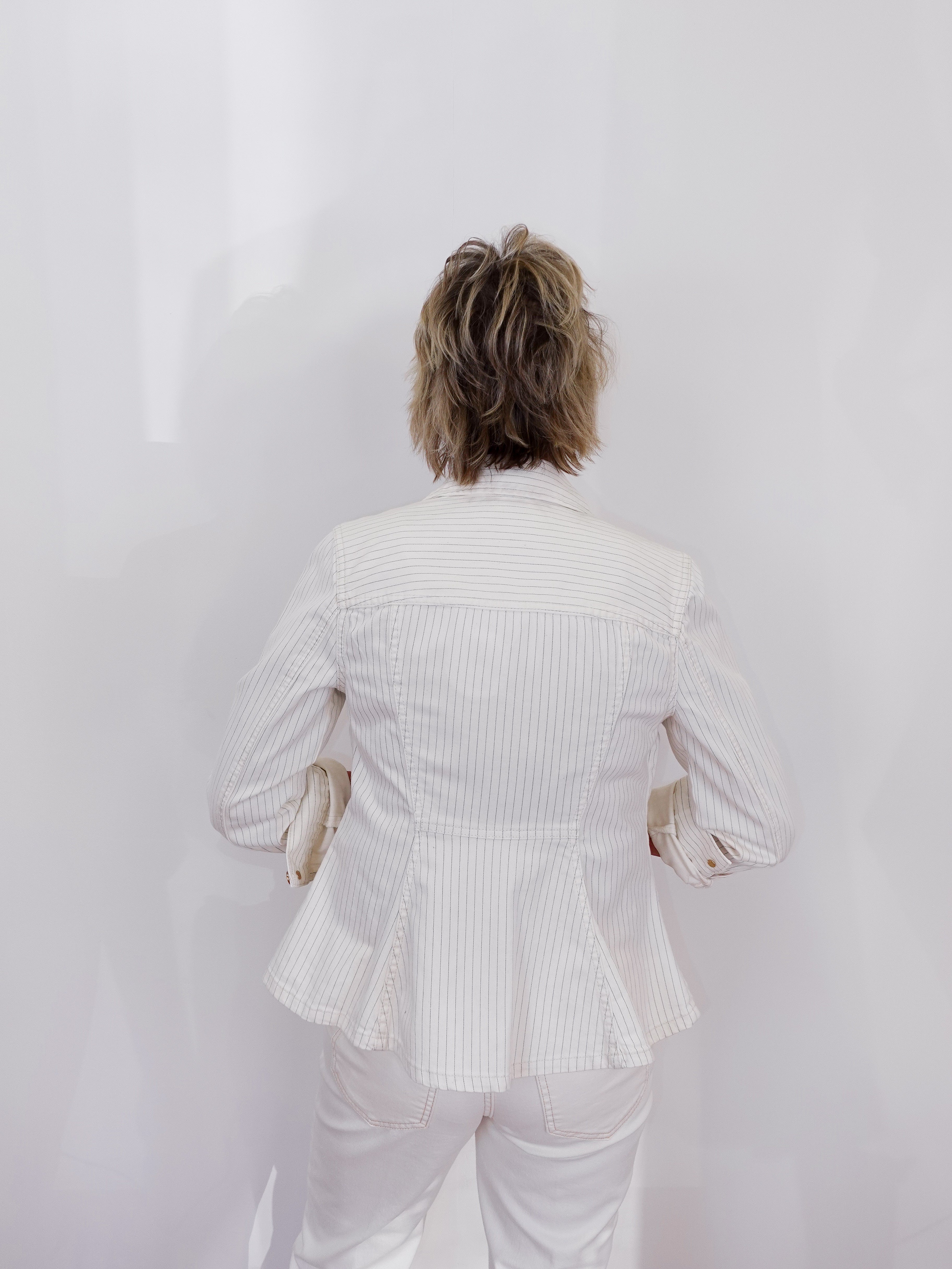 Person wearing a white ribbed blazer and pants against a plain background