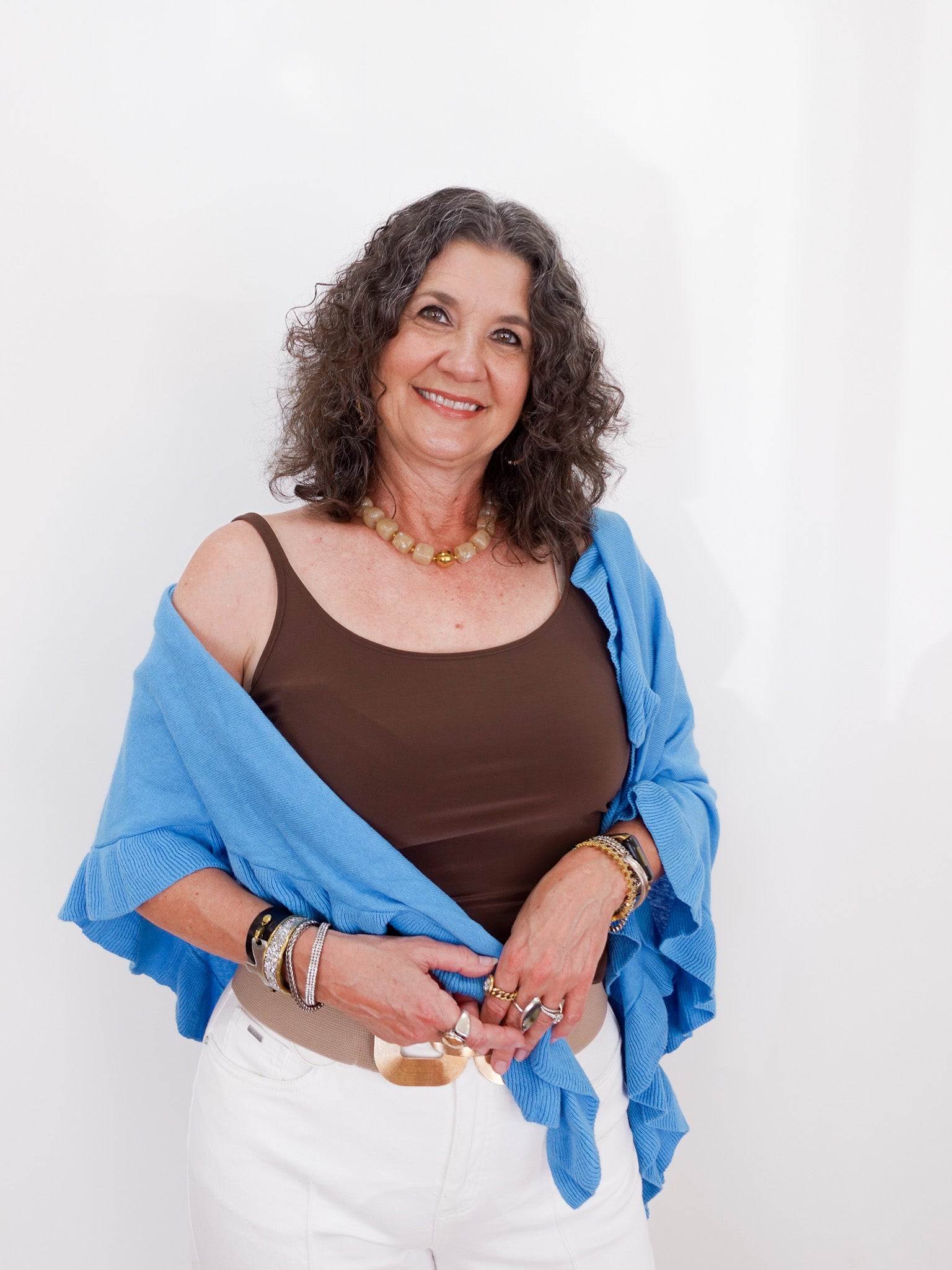 Woman wearing a blue shawl over a brown top on a white background