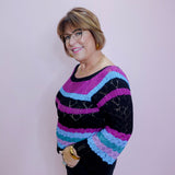 Person wearing a colorful striped sweater against a plain background