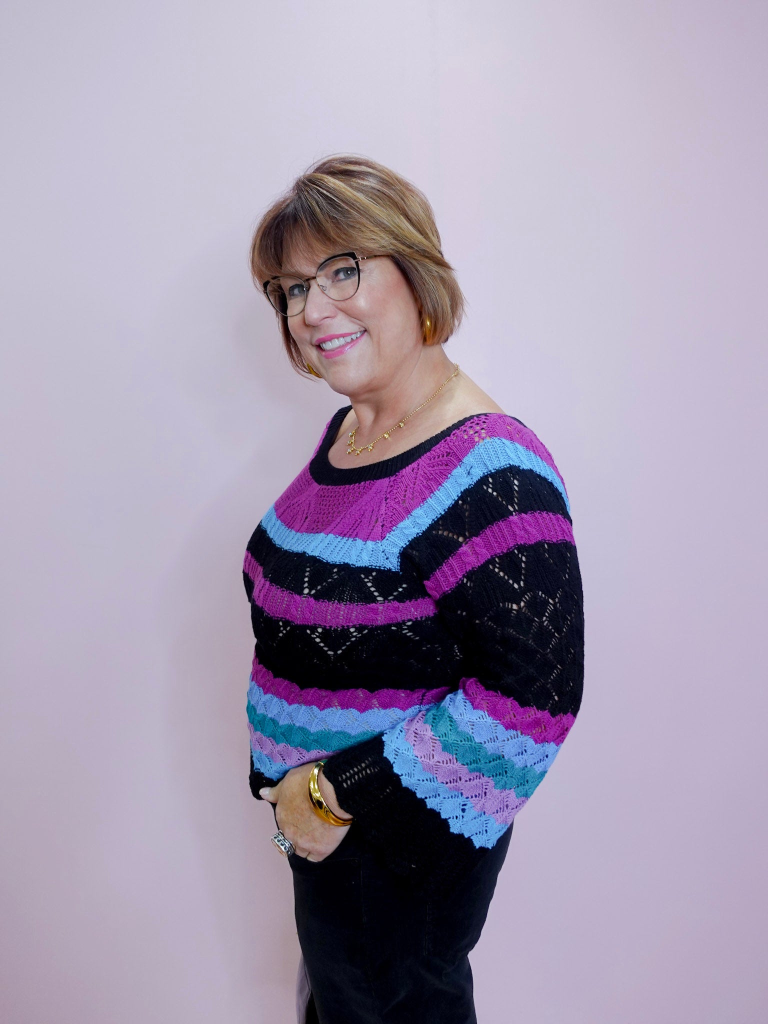 Person wearing a colorful striped sweater against a plain background
