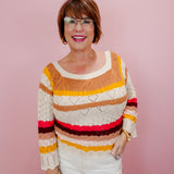 Woman wearing a colorful striped sweater against a pink background