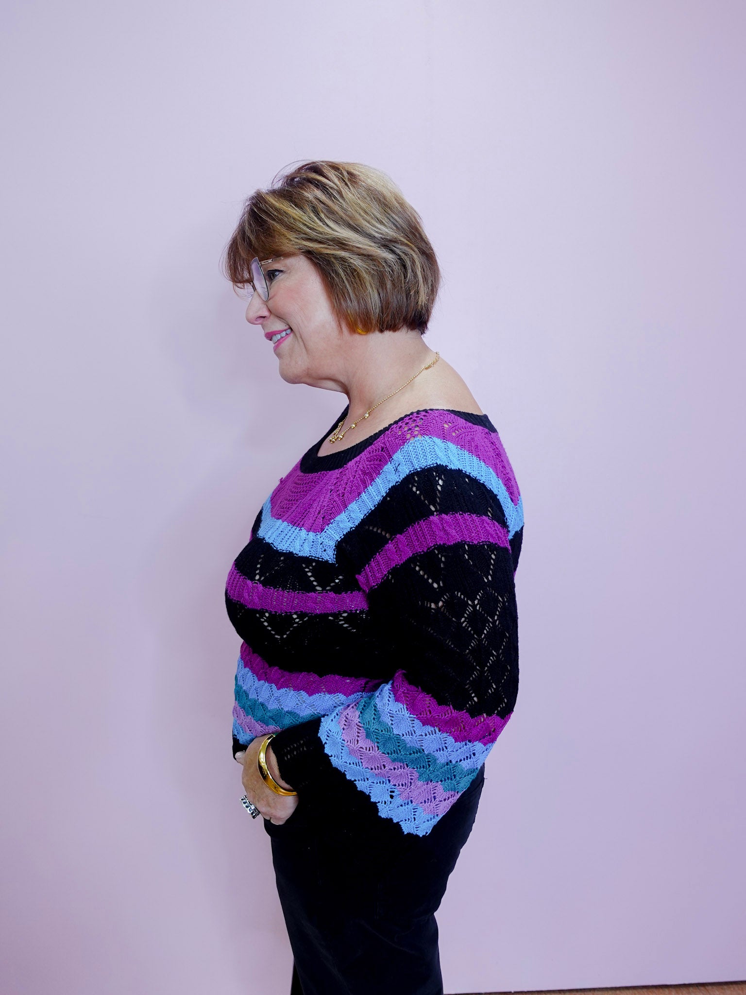 Person wearing a colorful striped sweater against a plain background
