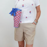 Person wearing a white t-shirt with red, blue, and yellow designs, holding a red, white, and blue patterned cup.