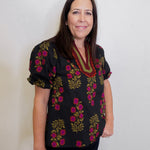 Woman wearing a black floral blouse against a white background