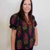 Woman wearing a black floral blouse against a white background
