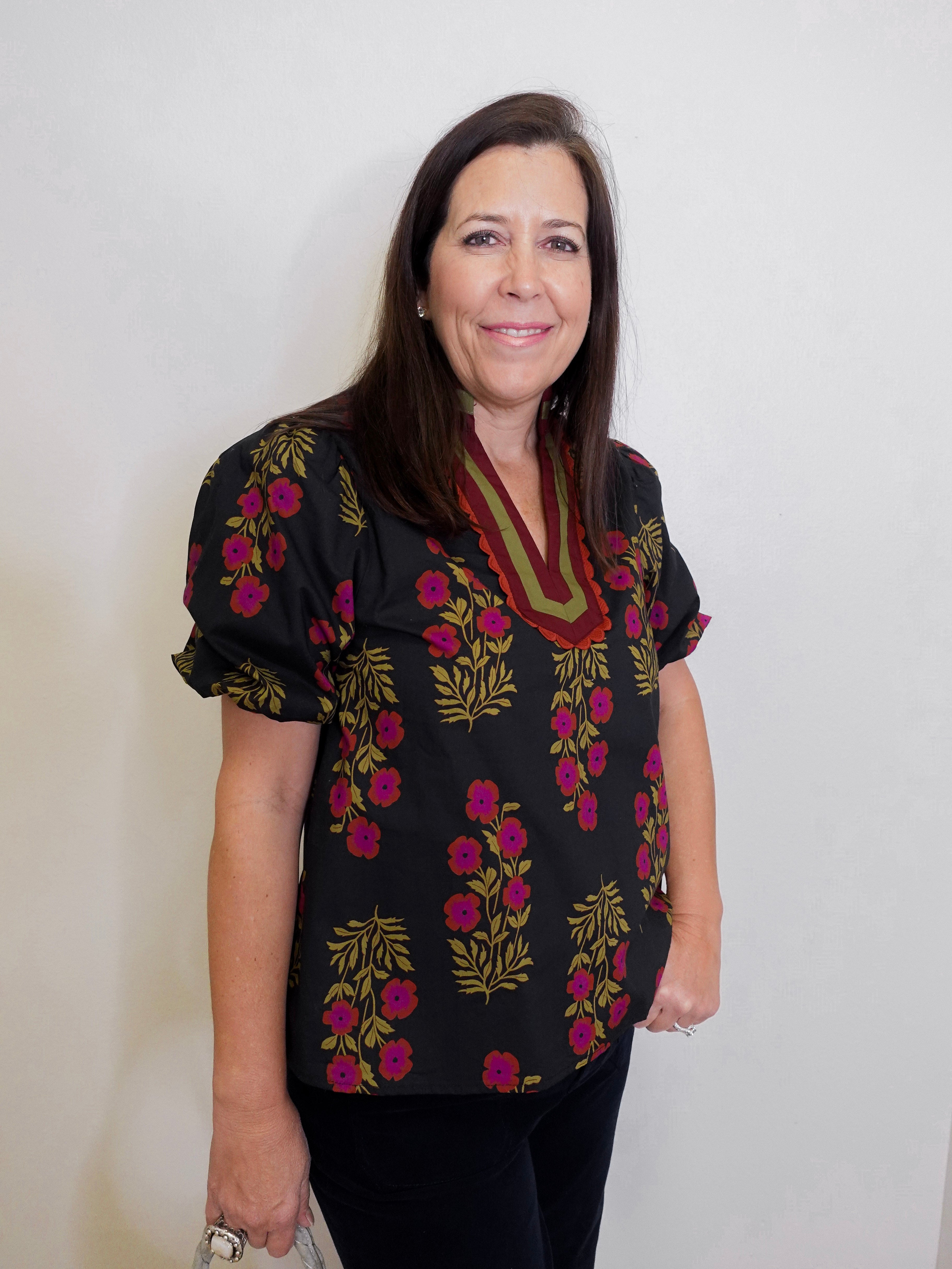 Woman wearing a black floral blouse against a white background