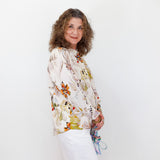 Woman wearing a floral blouse and white skirt against a plain background