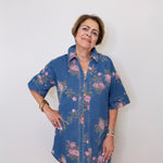 Woman wearing a blue floral dress against a white wall