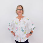 Woman wearing a white blouse with floral embroidery on a white background