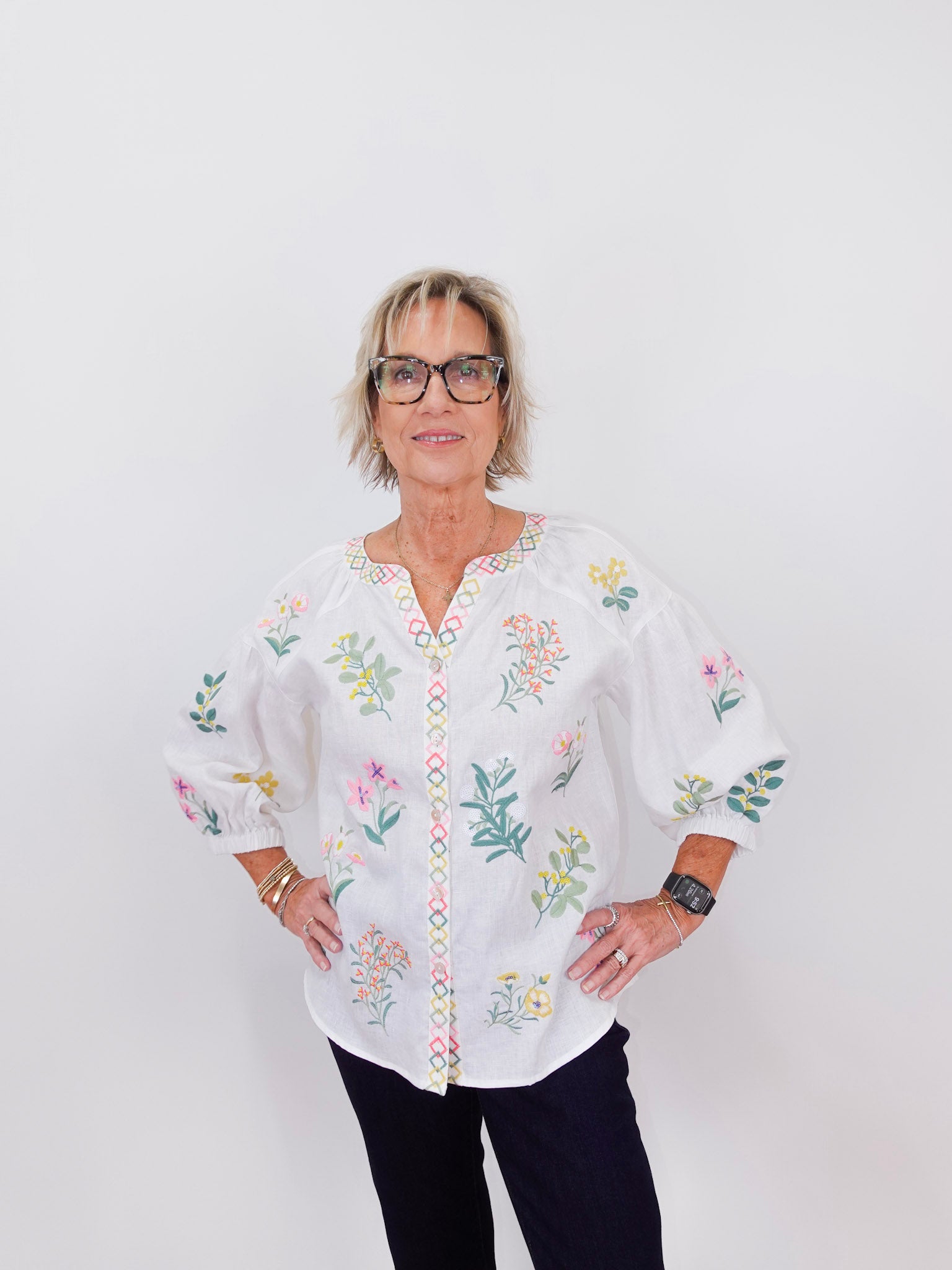 Woman wearing a white blouse with floral embroidery on a white background