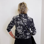 Person wearing a black and white patterned jacket against a white wall