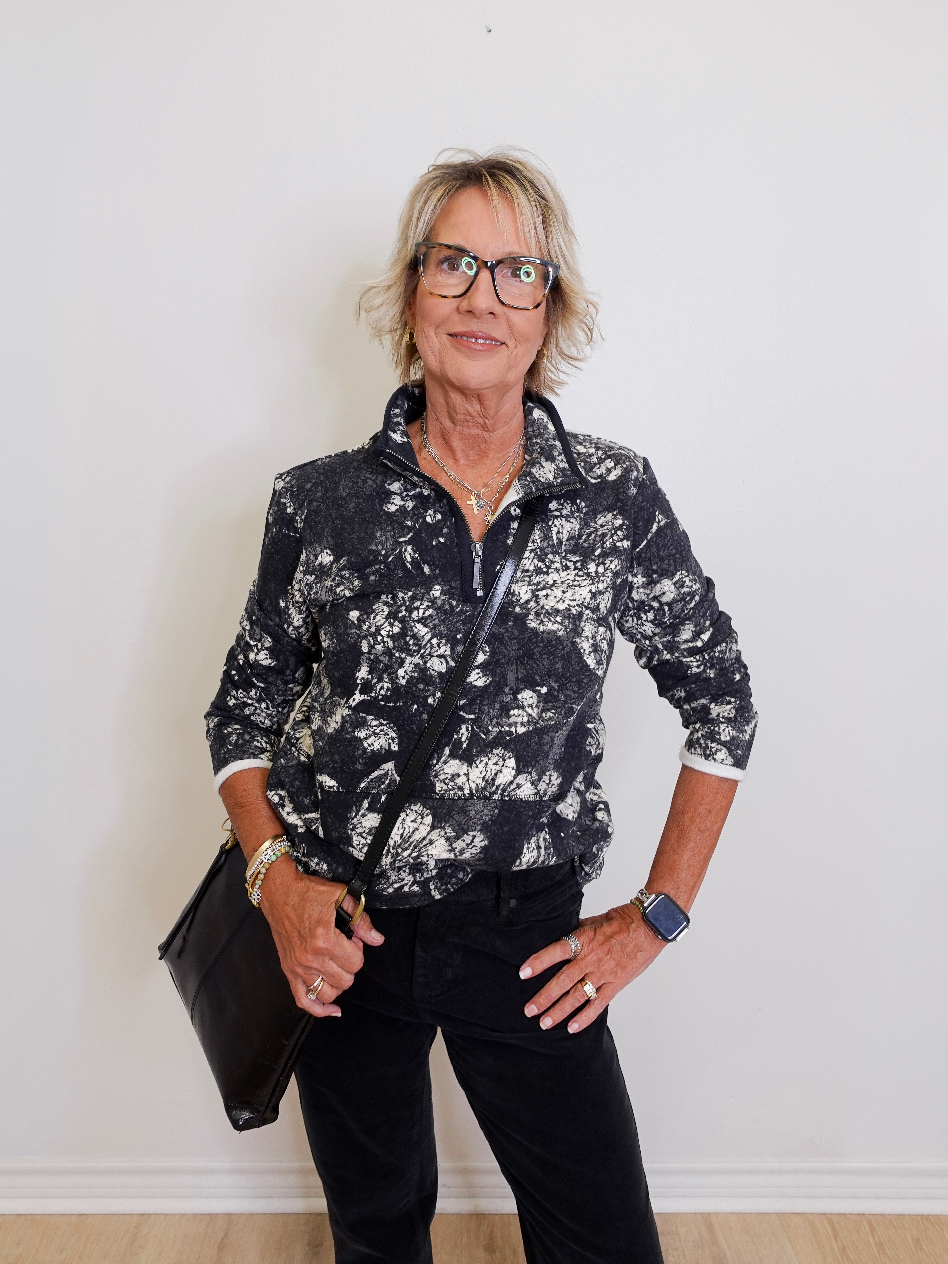Woman wearing a black and white floral jacket with a plain background