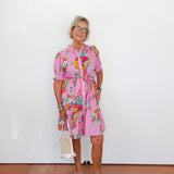 Woman wearing a pink floral dress against a white background