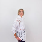 Person wearing a white floral blouse against a plain background