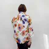 Person wearing a colorful floral shirt against a white wall