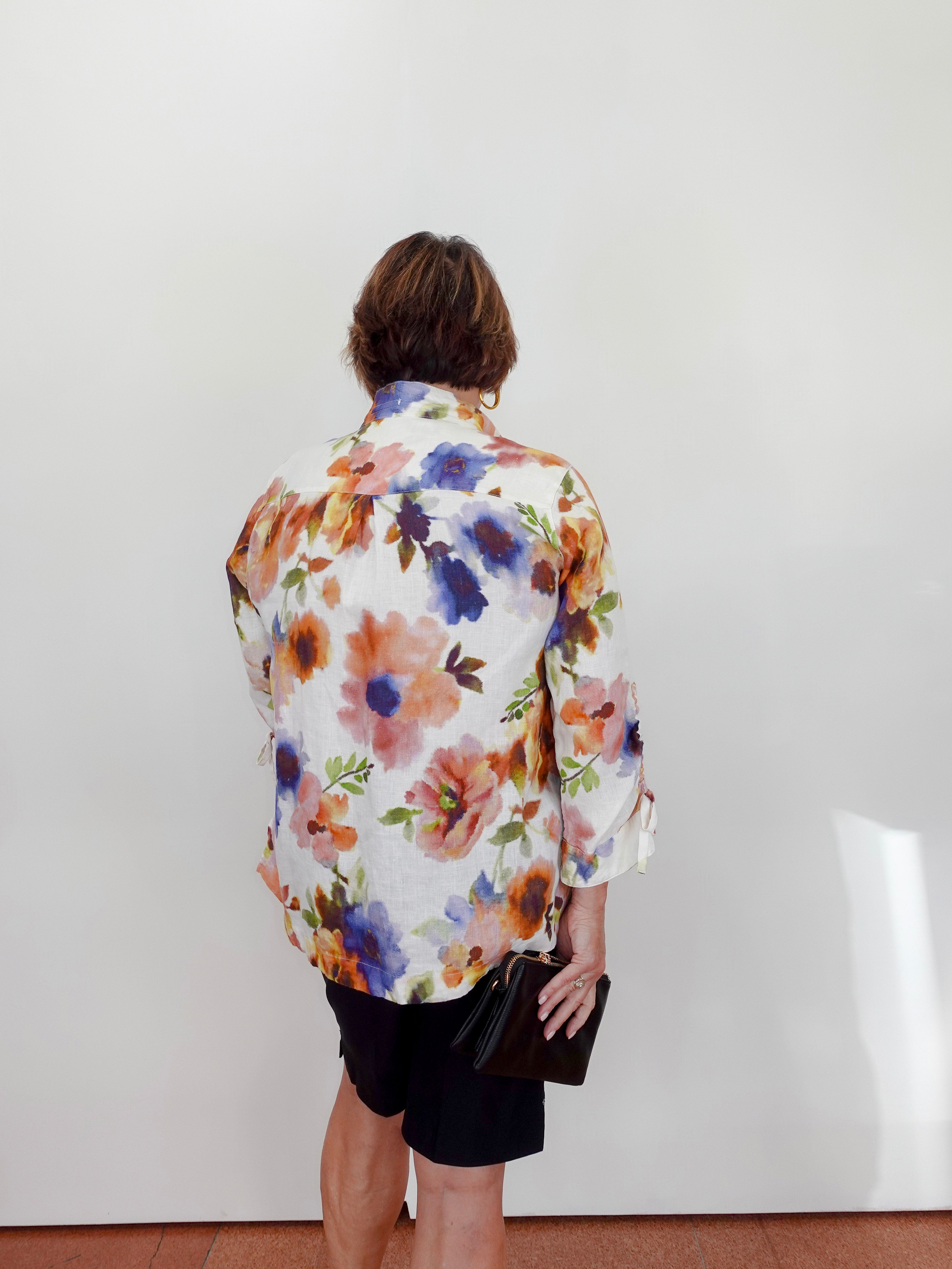 Person wearing a colorful floral shirt against a white wall