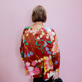 Person wearing a colorful floral jacket against a pink wall