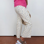 Person wearing floral pants and a pink top against a white wall.