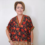 a women wearing a black floral short sleeve top in front of a white background 