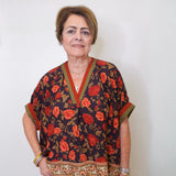 a women wearing a black floral short sleeve top in front of a white background 