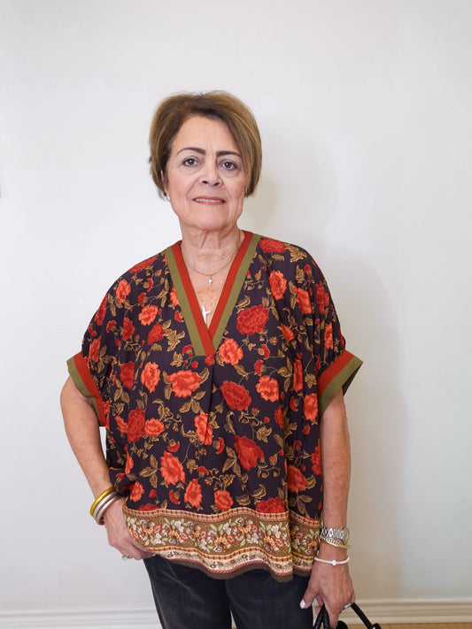 a women wearing a black floral short sleeve top in front of a white background 