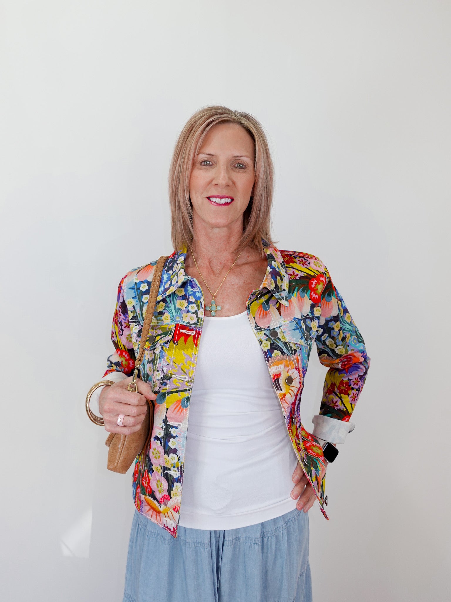 Woman wearing a colorful floral jacket against a white background