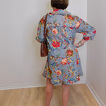 Person wearing a floral dress with a plain white wall background