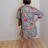 Person wearing a floral dress with a plain white wall background