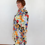 Woman wearing a colorful floral dress against a white background