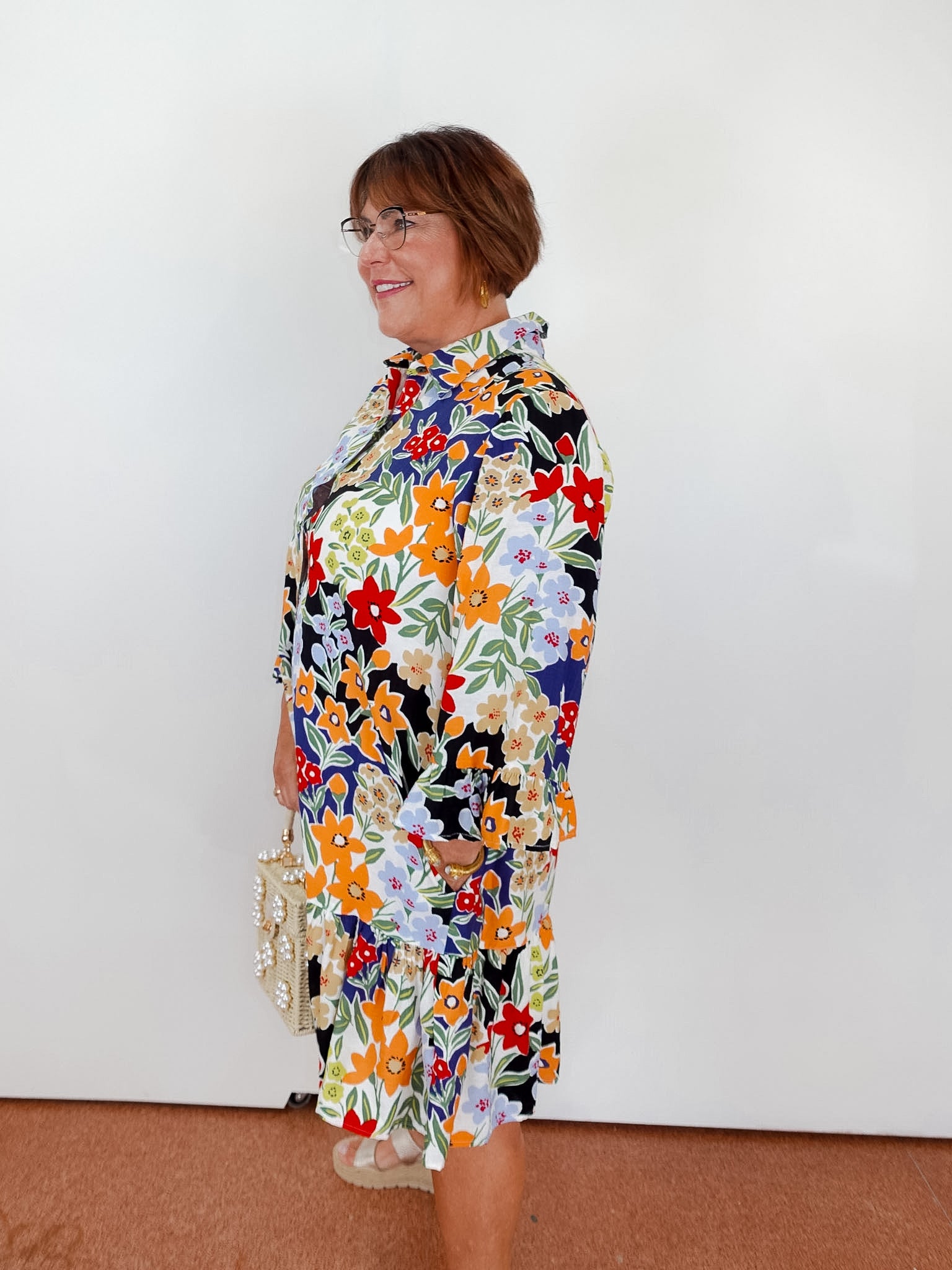 Woman wearing a colorful floral dress against a white background