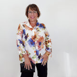 Woman wearing a colorful floral blouse and black shorts against a white background