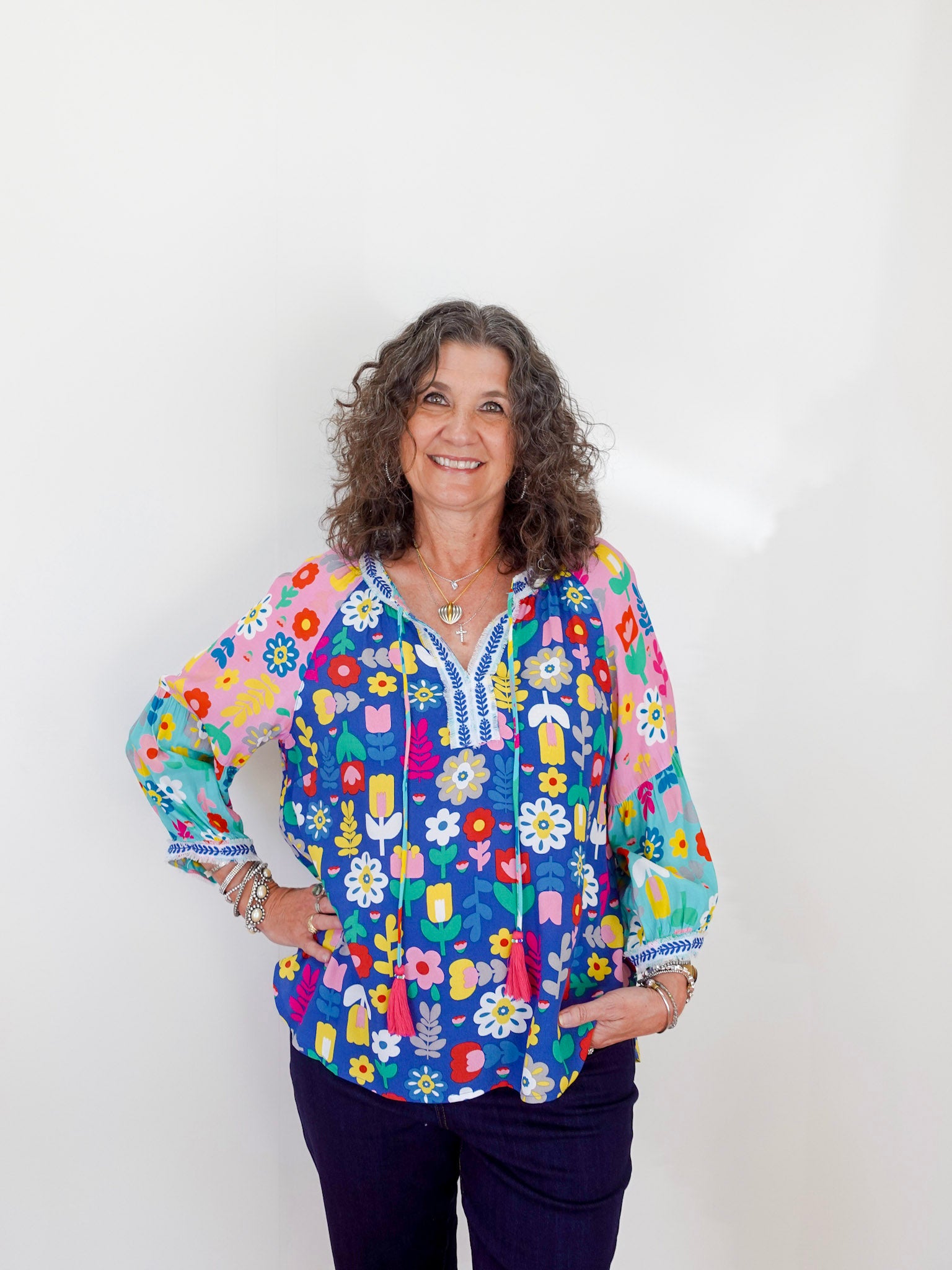 Woman wearing a colorful floral blouse against a white background