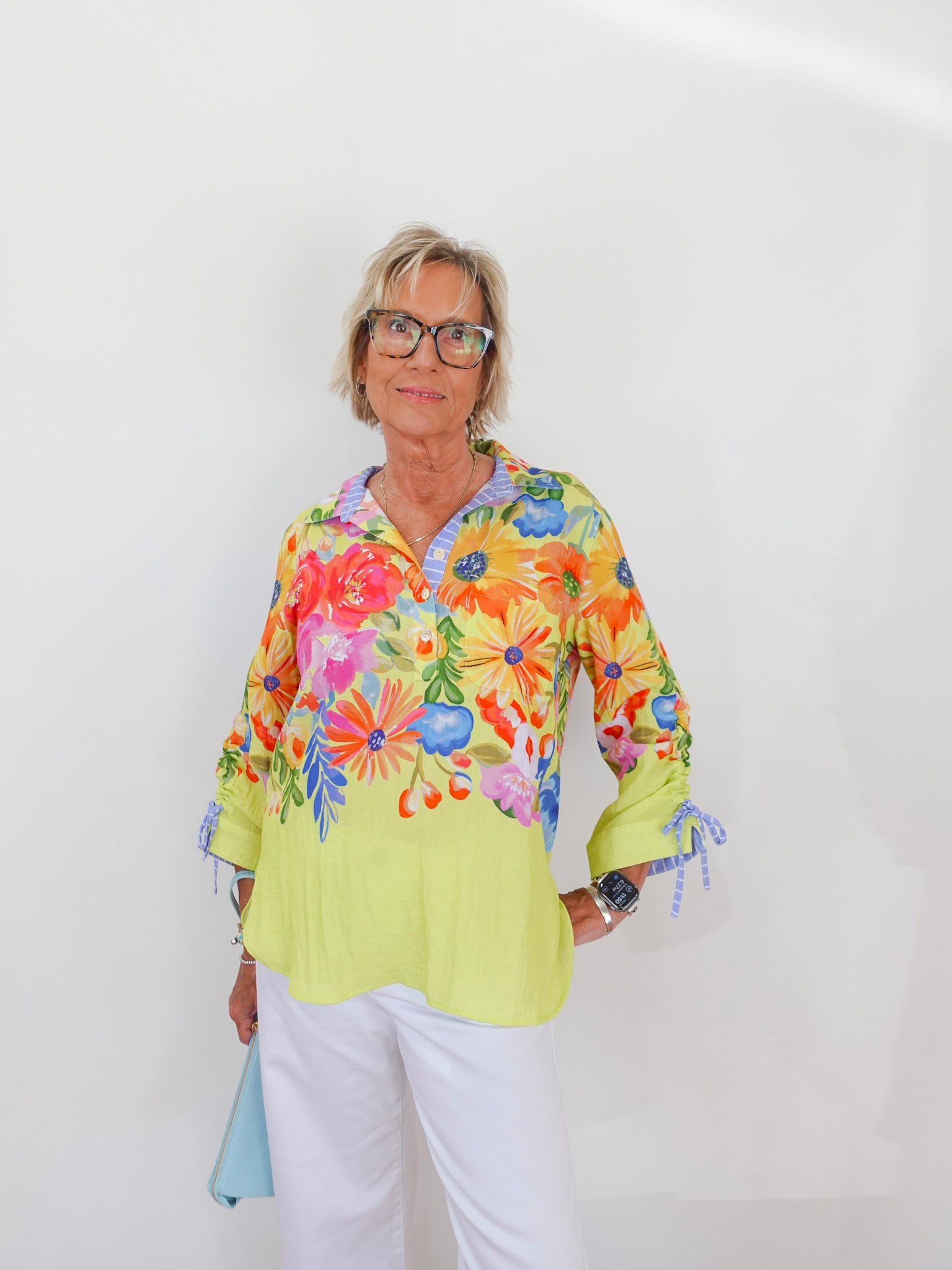 Woman wearing a colorful floral blouse against a white background
