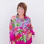 Woman wearing a colorful floral blouse with a pink border on a white background