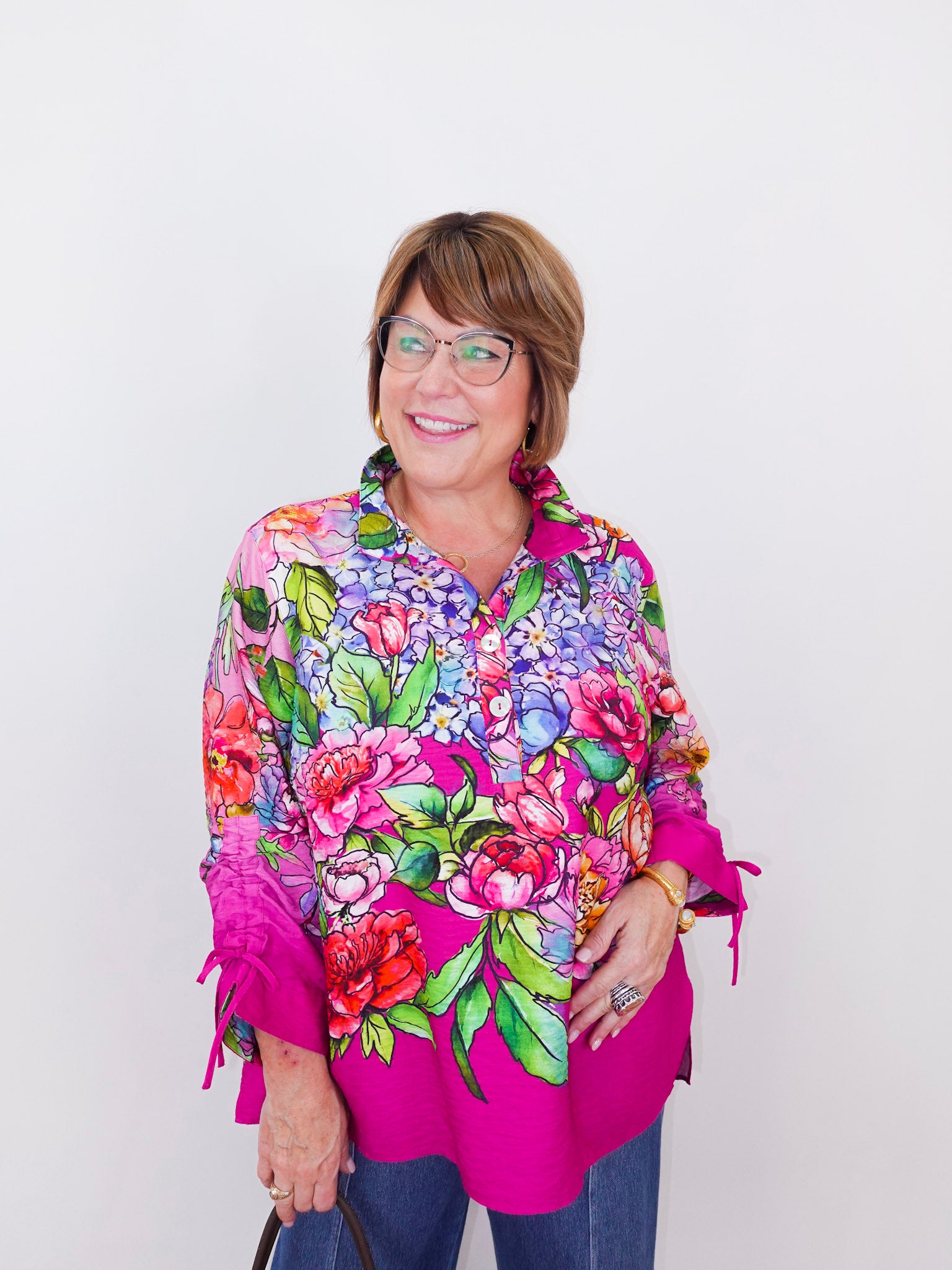 Woman wearing a colorful floral blouse with a pink border on a white background