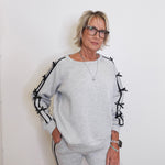 Woman wearing a gray sweater with black accents against a white background