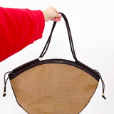 Person holding a straw handbag with black accents on a white background