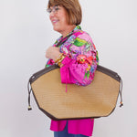 Person holding a large woven bag against a white background