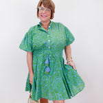 Woman wearing a green patterned dress with a white background