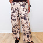 Person wearing floral pants and black shoes on a white background
