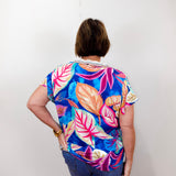 Person wearing a colorful floral shirt with their back to the camera on a white background