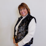 Woman wearing a patterned vest over a white shirt against a plain background