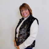 Woman wearing a patterned vest over a white shirt against a plain background