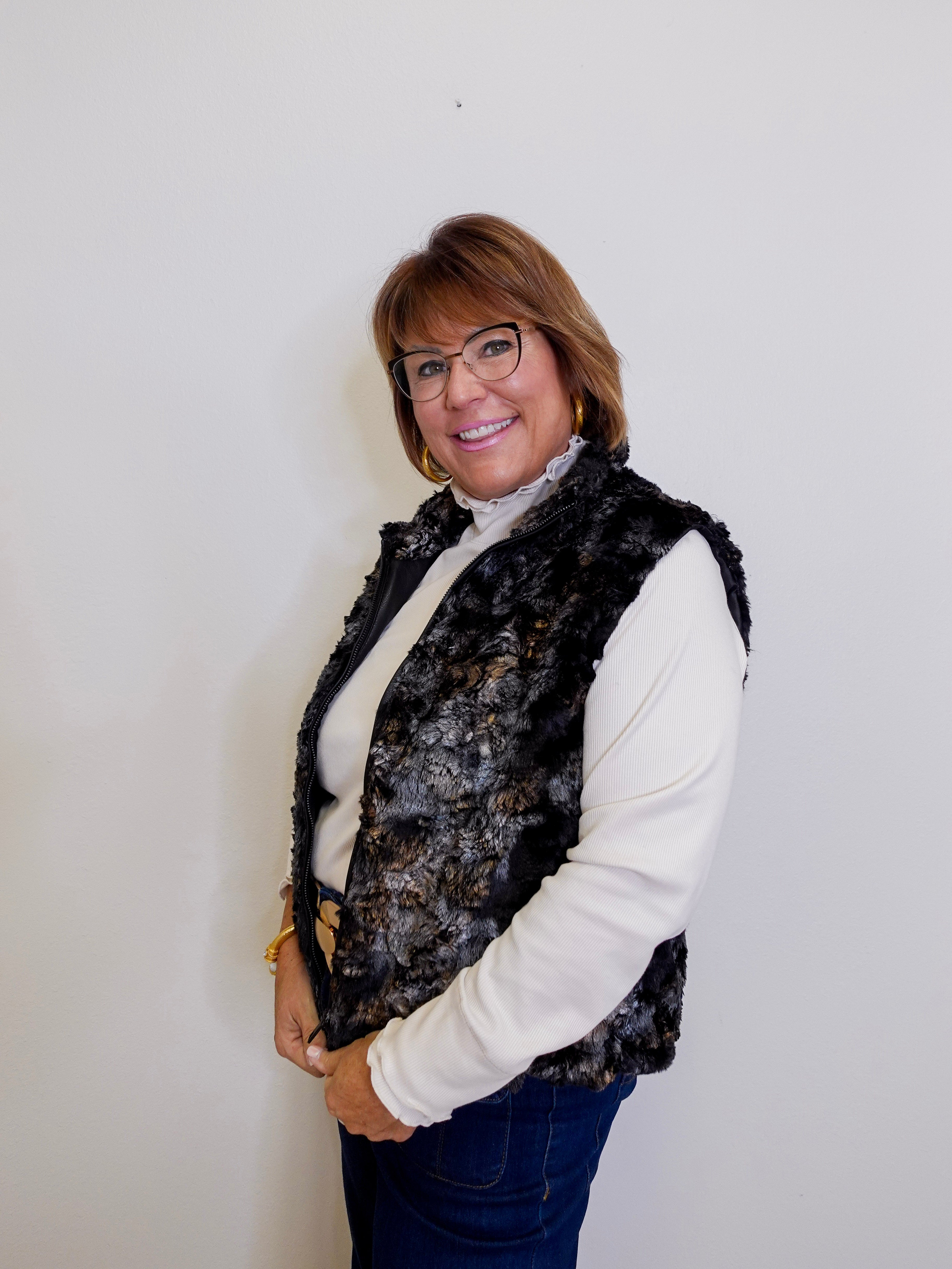 Woman wearing a patterned vest over a white shirt against a plain background