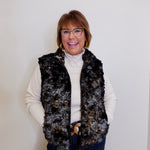 Woman wearing a patterned vest over a white turtleneck against a plain background