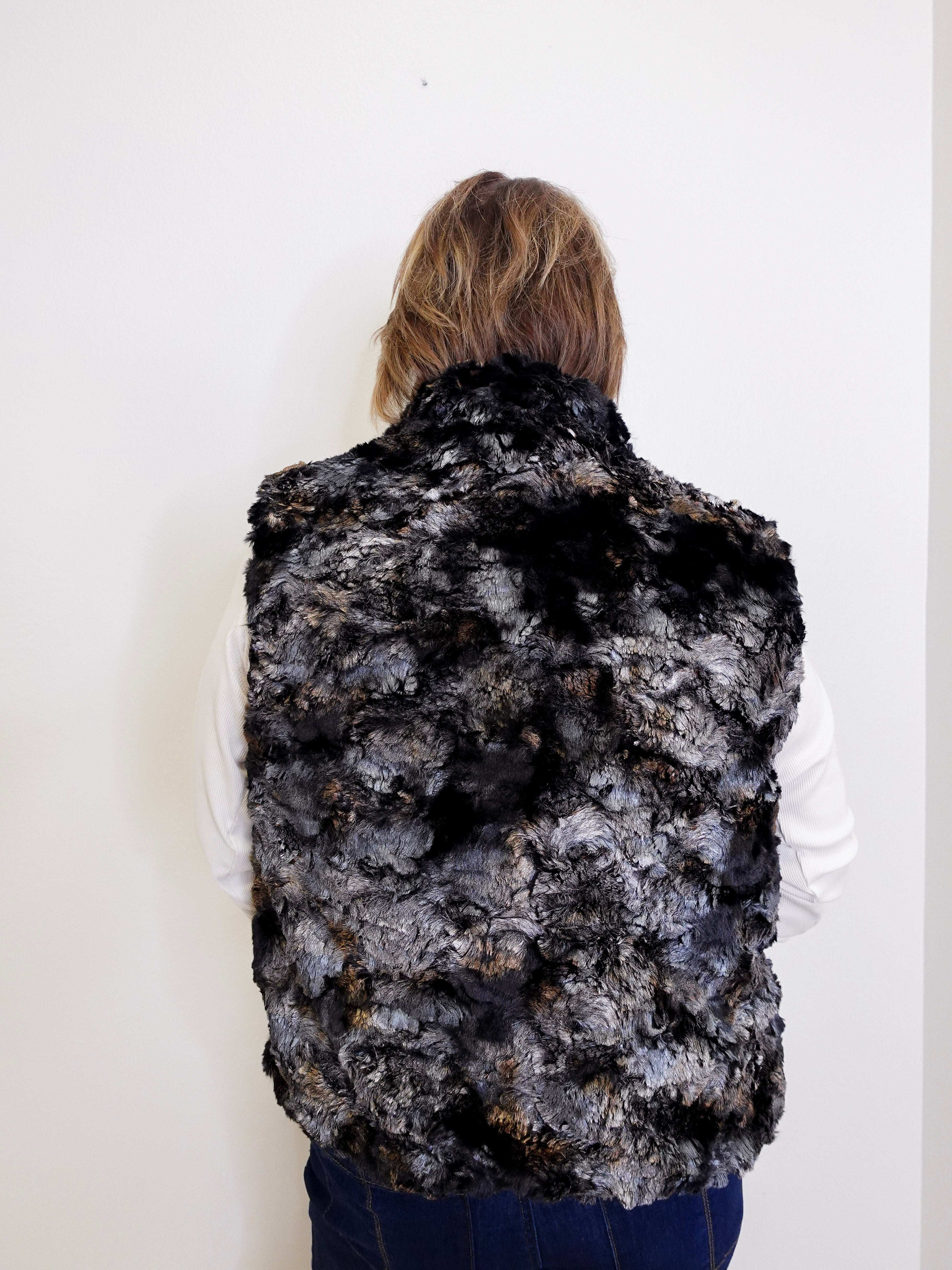 Person wearing a black and gray patterned fur vest against a white background