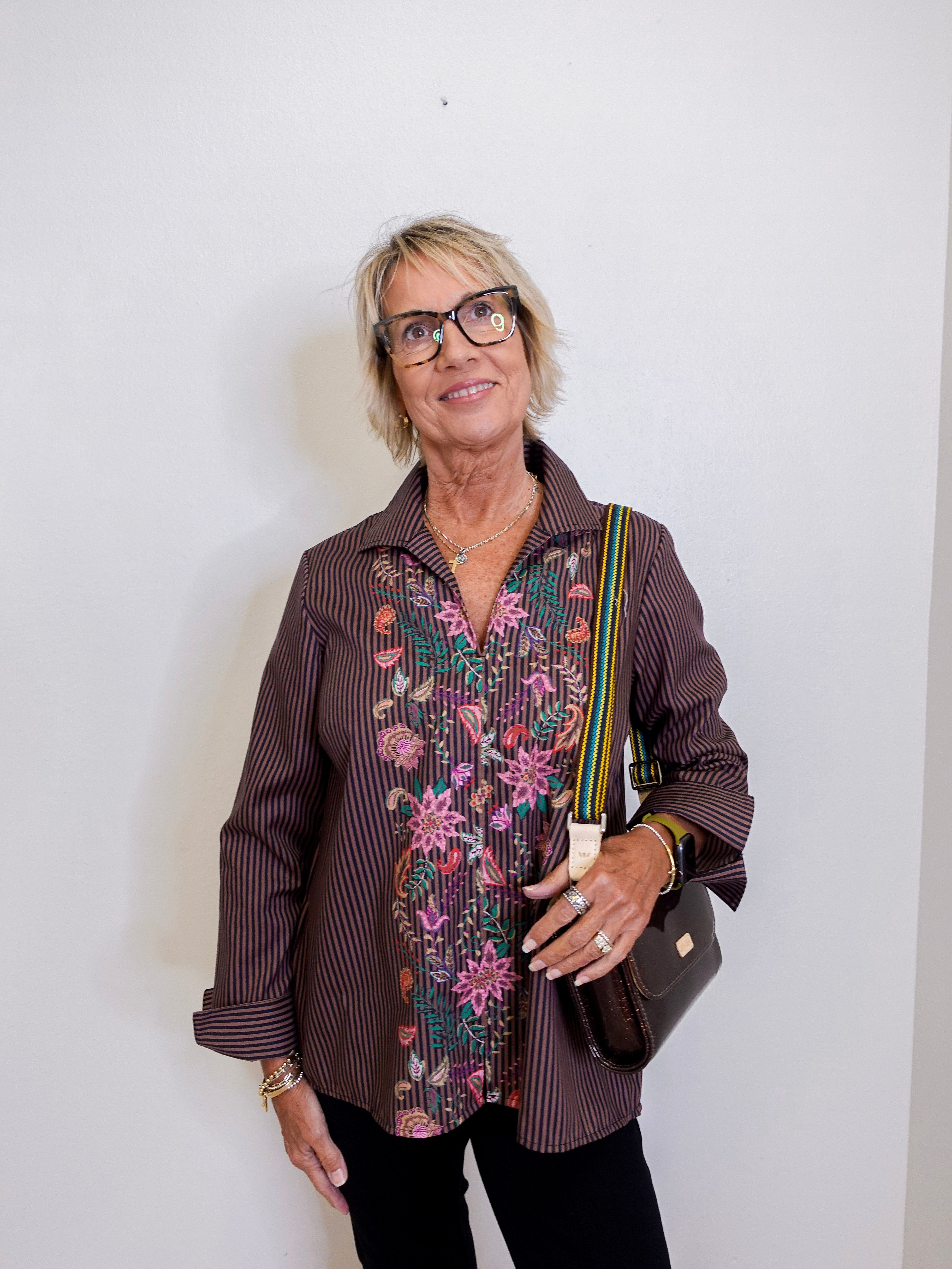Woman wearing a patterned blouse with a plain background