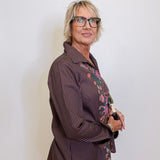 Woman wearing a brown striped shirt with floral patterns on a white background